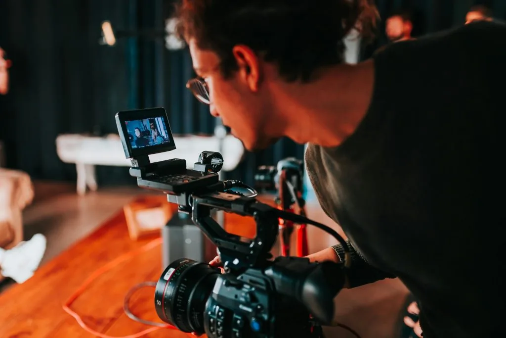 Professional camera recording a video, set up on a tripod with studio lighting and clear background.